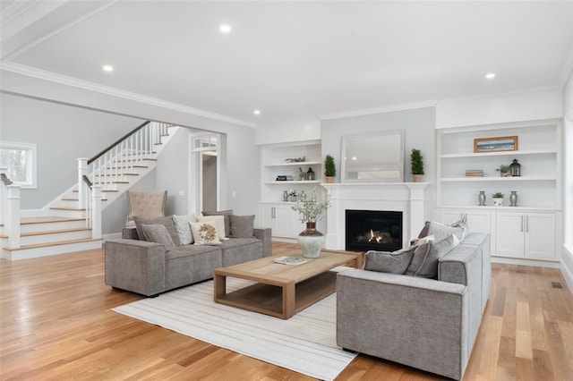 living room featuring crown molding, built in features, and light hardwood / wood-style floors