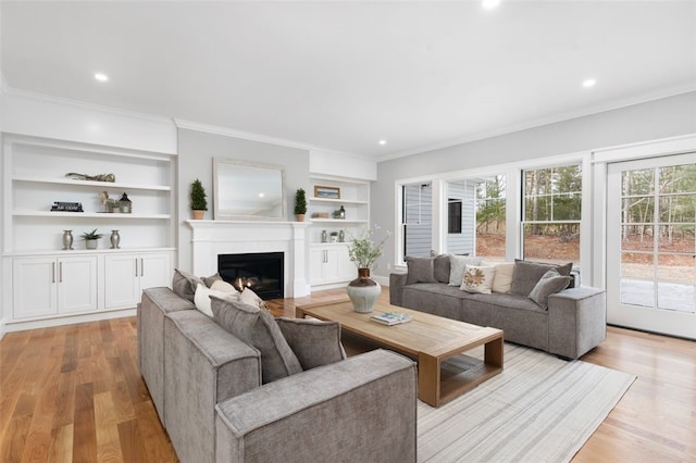 living room with light hardwood / wood-style flooring, built in features, and ornamental molding