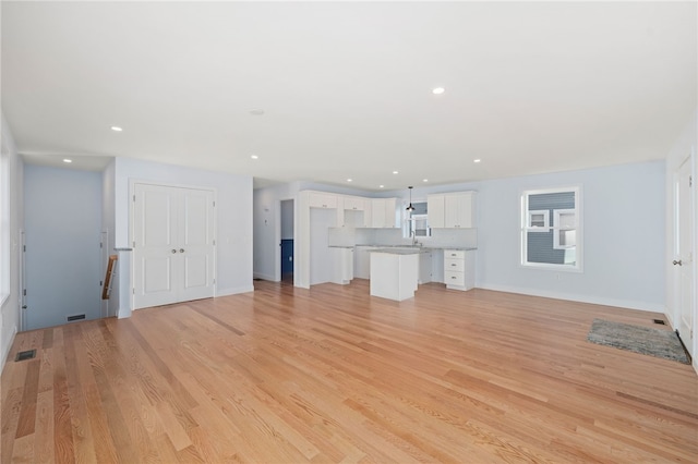 unfurnished living room with baseboards, light wood-type flooring, a sink, and recessed lighting