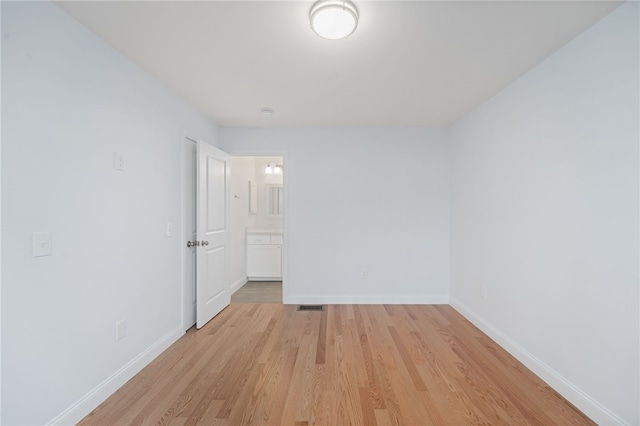 spare room with light wood finished floors, visible vents, and baseboards