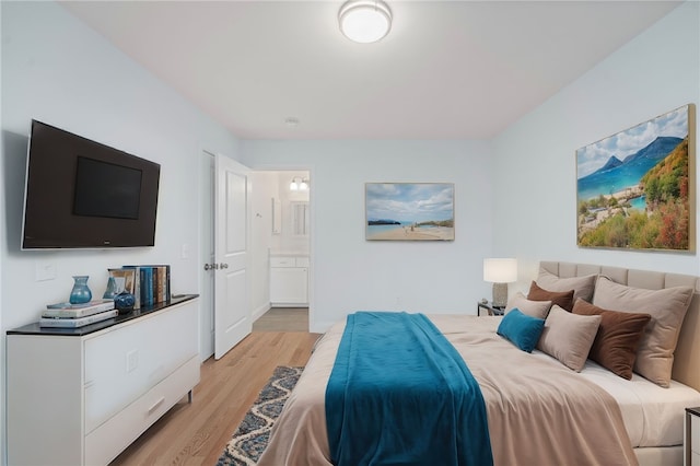 bedroom featuring light wood finished floors and connected bathroom