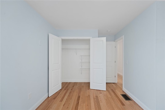 unfurnished bedroom featuring light wood finished floors, a closet, visible vents, and baseboards