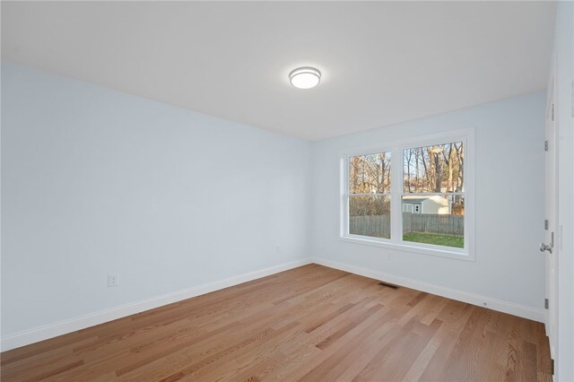 unfurnished room featuring visible vents, light wood-style flooring, and baseboards