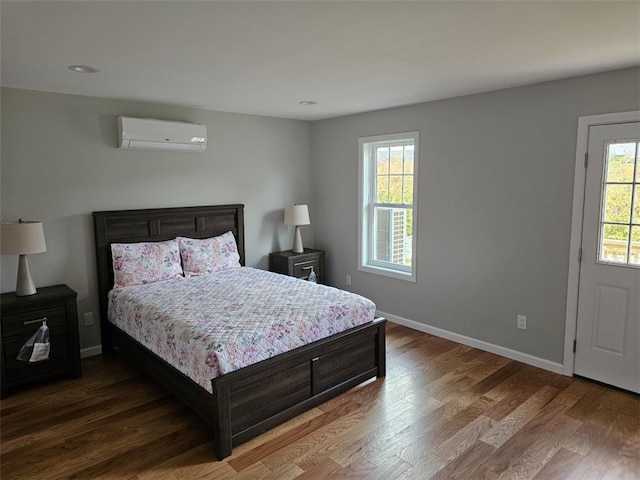 bedroom with hardwood / wood-style flooring, a wall unit AC, and multiple windows