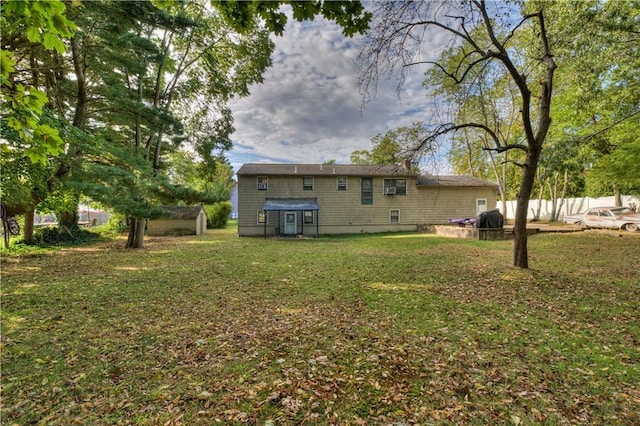 back of property featuring a storage unit and a lawn