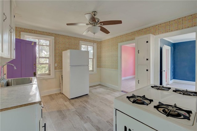 kitchen with ornamental molding, white appliances, ceiling fan, sink, and white cabinetry