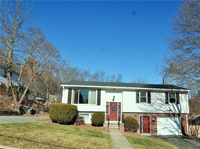 raised ranch featuring a garage and a front yard