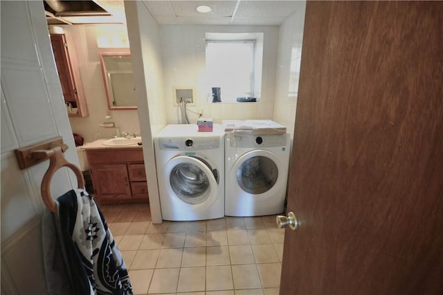 clothes washing area with independent washer and dryer, light tile patterned floors, and sink