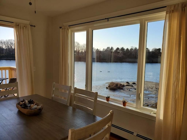 dining room featuring a water view, wood-type flooring, and a baseboard heating unit