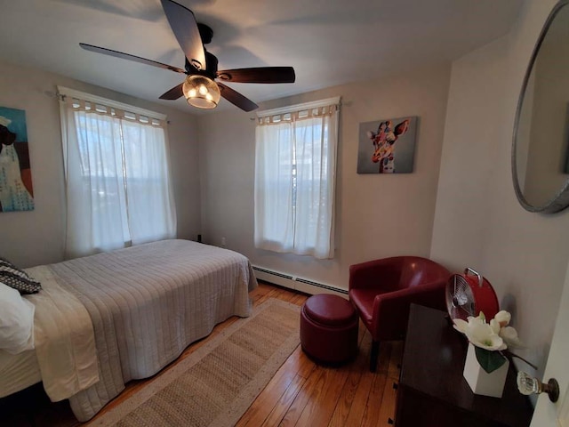 bedroom featuring ceiling fan, wood-type flooring, and a baseboard heating unit