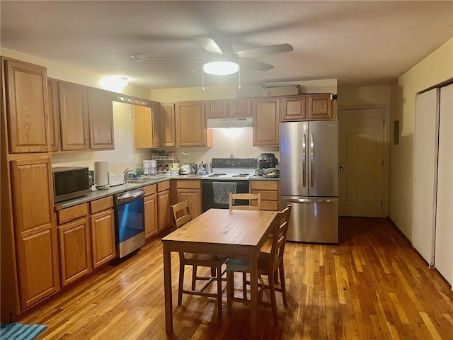 kitchen with light hardwood / wood-style flooring, stainless steel appliances, a textured ceiling, and sink