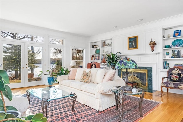 living room featuring french doors, light wood-type flooring, crown molding, and a premium fireplace