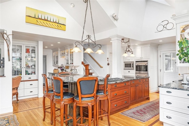 kitchen with a kitchen bar, appliances with stainless steel finishes, decorative light fixtures, and light hardwood / wood-style flooring