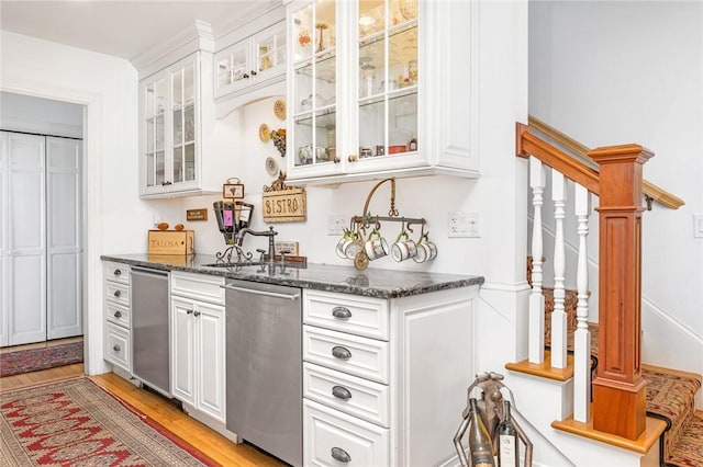 bar featuring dishwasher, light wood-type flooring, white cabinetry, and dark stone countertops