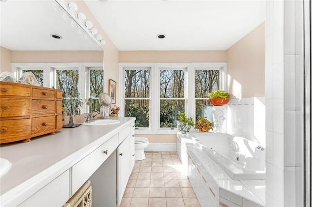 bathroom with tile patterned floors, a washtub, vanity, and toilet