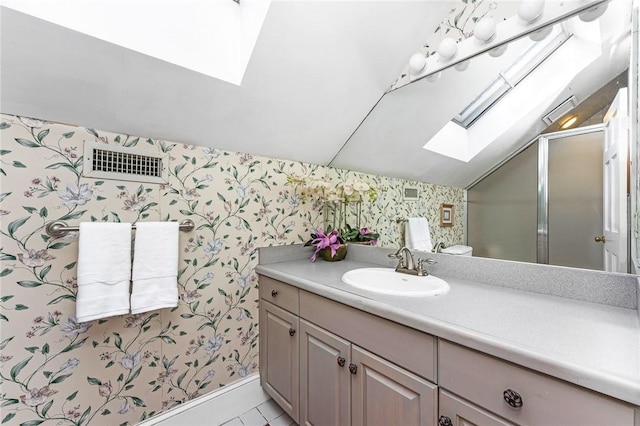 bathroom with tile patterned floors, an enclosed shower, vanity, lofted ceiling with skylight, and toilet