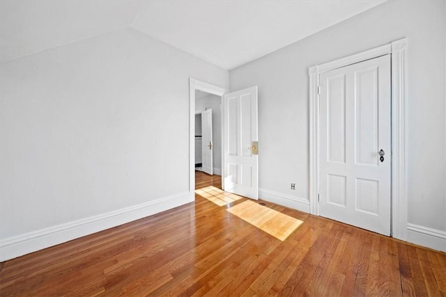 unfurnished bedroom featuring hardwood / wood-style floors and vaulted ceiling