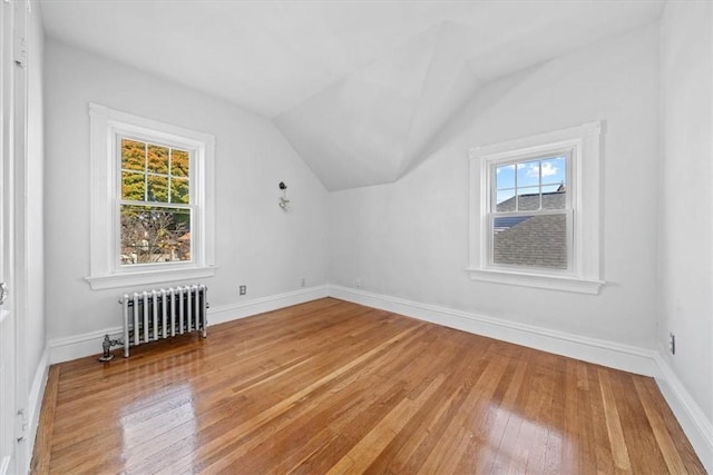 additional living space with radiator, plenty of natural light, and wood-type flooring