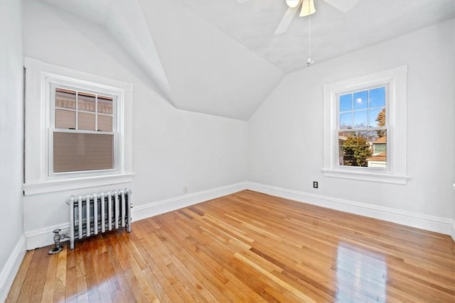 additional living space with ceiling fan, radiator heating unit, vaulted ceiling, and hardwood / wood-style flooring