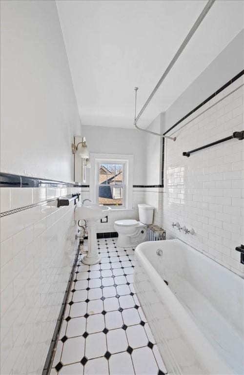 bathroom with toilet, tile walls, and tiled shower / bath