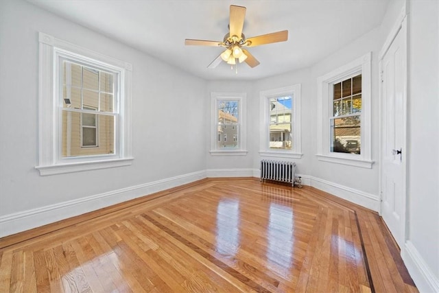 empty room featuring radiator, ceiling fan, and wood-type flooring