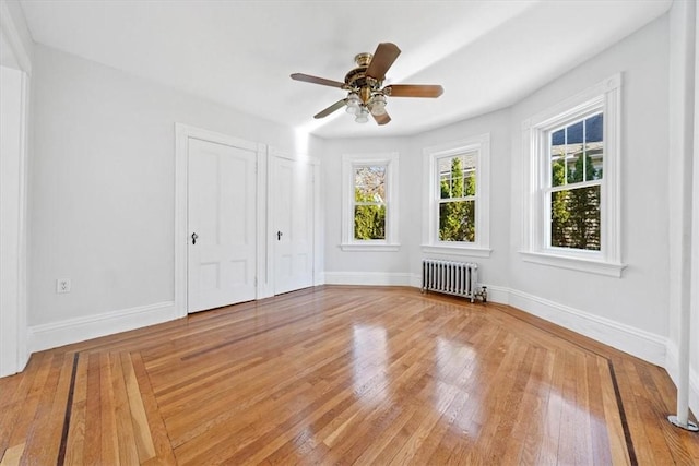 unfurnished bedroom featuring radiator, ceiling fan, and wood-type flooring