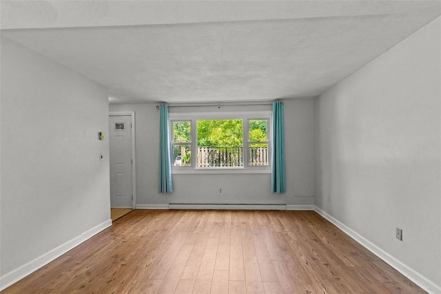 spare room with light hardwood / wood-style flooring, a baseboard radiator, and a textured ceiling