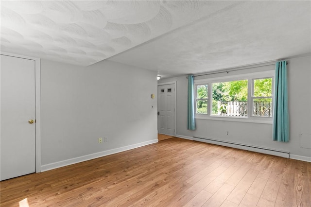 empty room with a baseboard radiator and light hardwood / wood-style floors