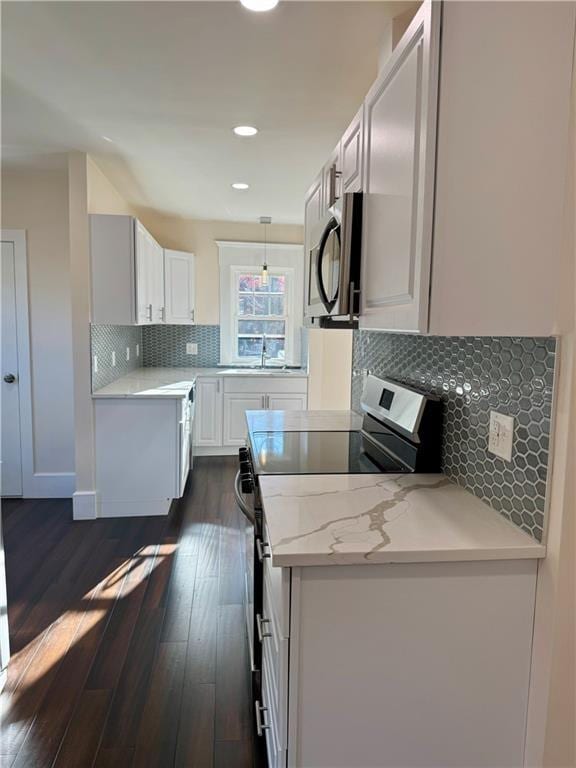 kitchen featuring pendant lighting, appliances with stainless steel finishes, tasteful backsplash, dark hardwood / wood-style flooring, and white cabinetry