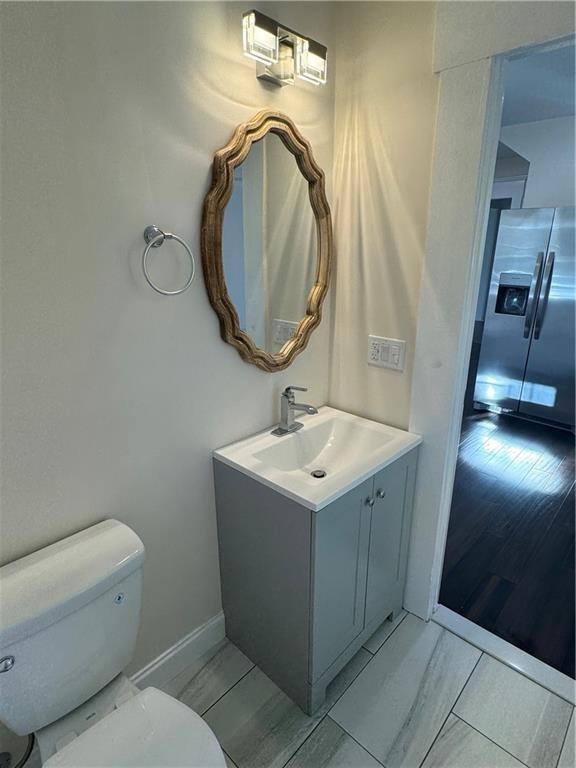 bathroom with hardwood / wood-style flooring, vanity, and toilet