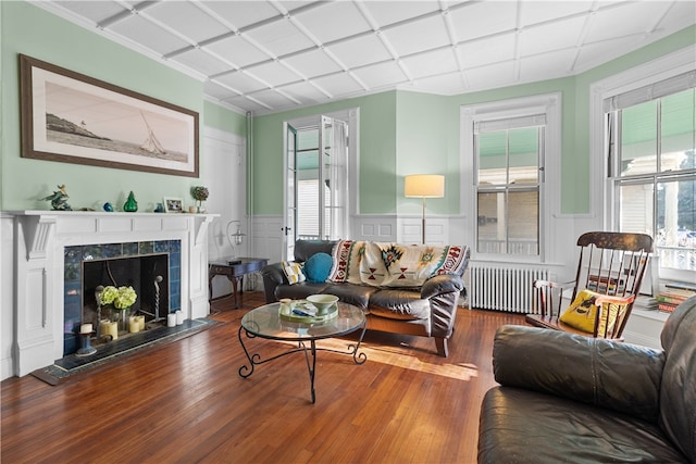 living room featuring hardwood / wood-style floors, radiator heating unit, and a tiled fireplace