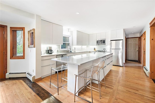 kitchen featuring white cabinets, appliances with stainless steel finishes, a kitchen bar, and a kitchen island