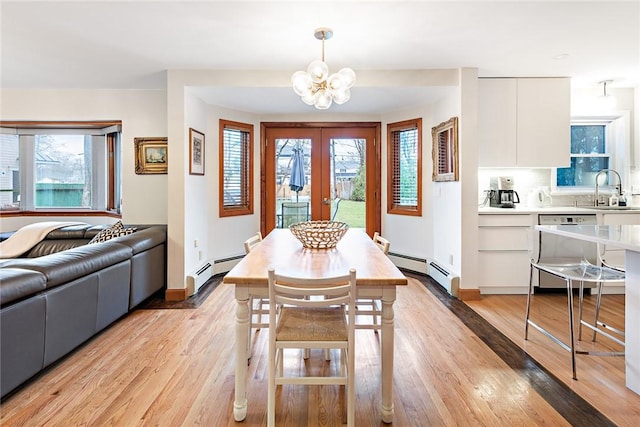 dining room featuring a notable chandelier, light hardwood / wood-style floors, baseboard heating, and a wealth of natural light