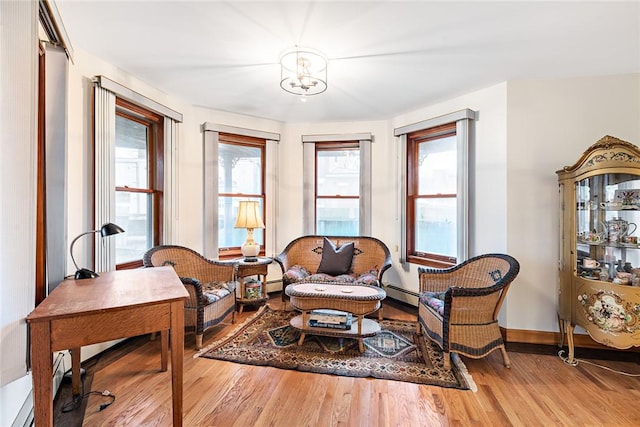 living area with hardwood / wood-style flooring, an inviting chandelier, and plenty of natural light