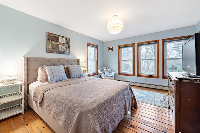 bedroom with light hardwood / wood-style floors and a baseboard radiator