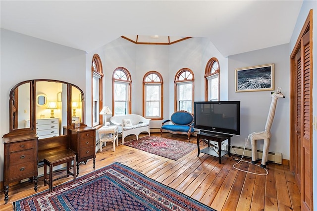 living area with baseboard heating, wood-type flooring, and lofted ceiling