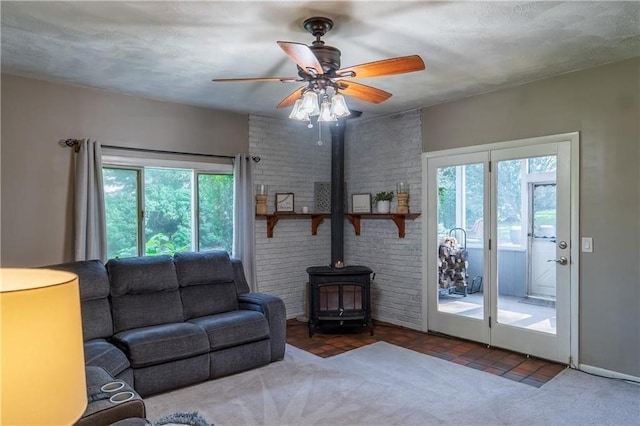 living room featuring ceiling fan, a wood stove, and a textured ceiling