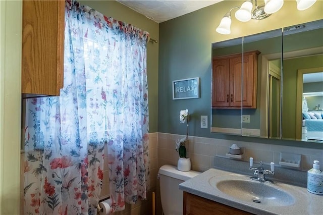 bathroom with vanity, toilet, and tile walls