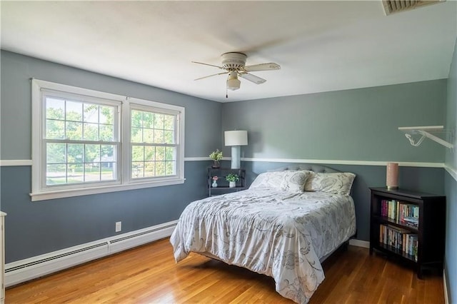 bedroom featuring ceiling fan, hardwood / wood-style flooring, and a baseboard heating unit