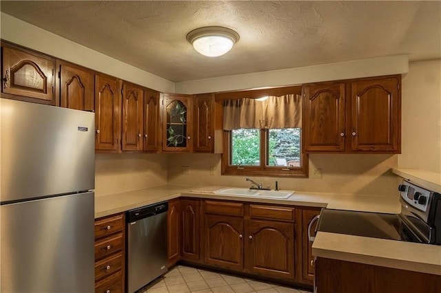 kitchen with a textured ceiling, sink, and stainless steel appliances