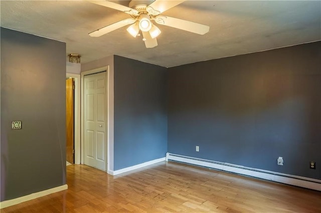 spare room with ceiling fan, light wood-type flooring, and a baseboard heating unit