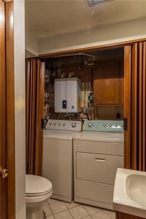 bathroom featuring tile patterned floors, vanity, water heater, independent washer and dryer, and toilet