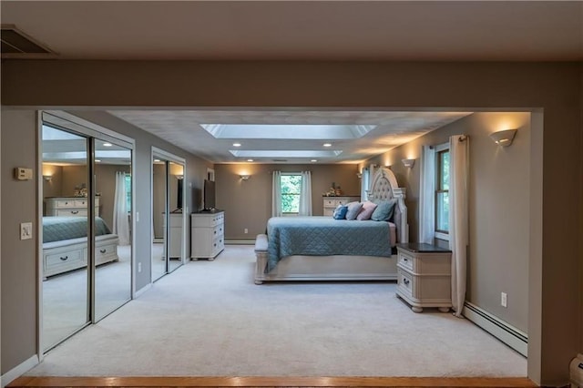 carpeted bedroom featuring a skylight and a baseboard heating unit