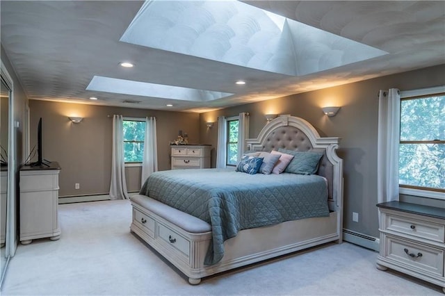 bedroom with a baseboard heating unit, a skylight, and multiple windows