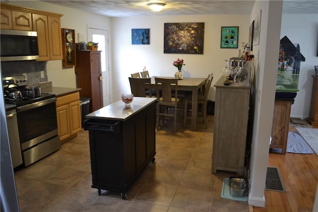 kitchen featuring a center island, dark hardwood / wood-style flooring, a textured ceiling, decorative backsplash, and appliances with stainless steel finishes