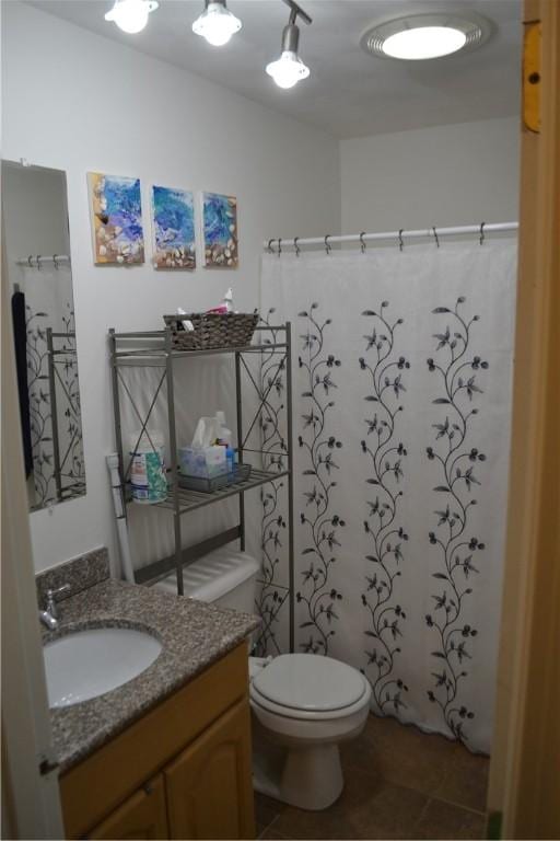 bathroom featuring tile patterned flooring, vanity, toilet, and walk in shower