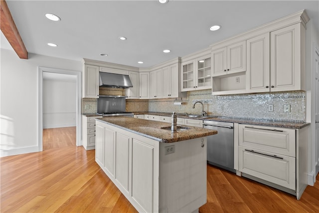 kitchen with decorative backsplash, stainless steel dishwasher, wall chimney exhaust hood, light hardwood / wood-style floors, and white cabinetry