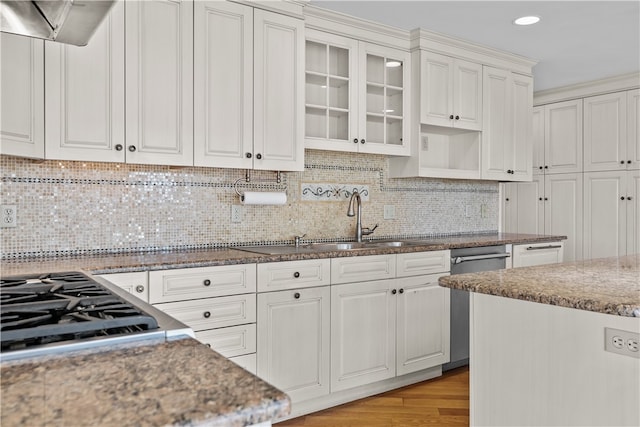 kitchen with appliances with stainless steel finishes, light wood-type flooring, backsplash, ventilation hood, and white cabinets