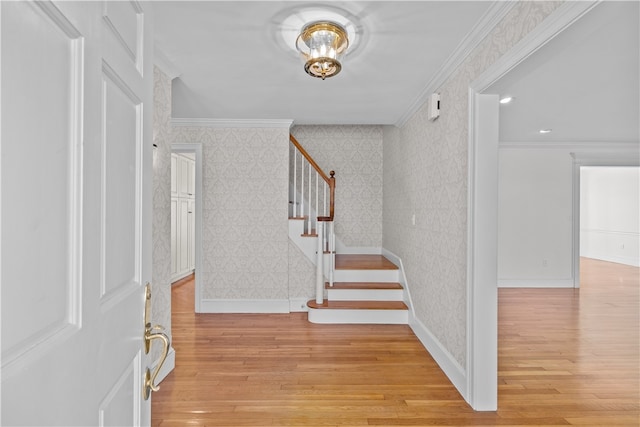 foyer with light wood-type flooring and crown molding