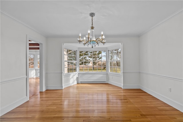 unfurnished dining area with light hardwood / wood-style floors, crown molding, and an inviting chandelier